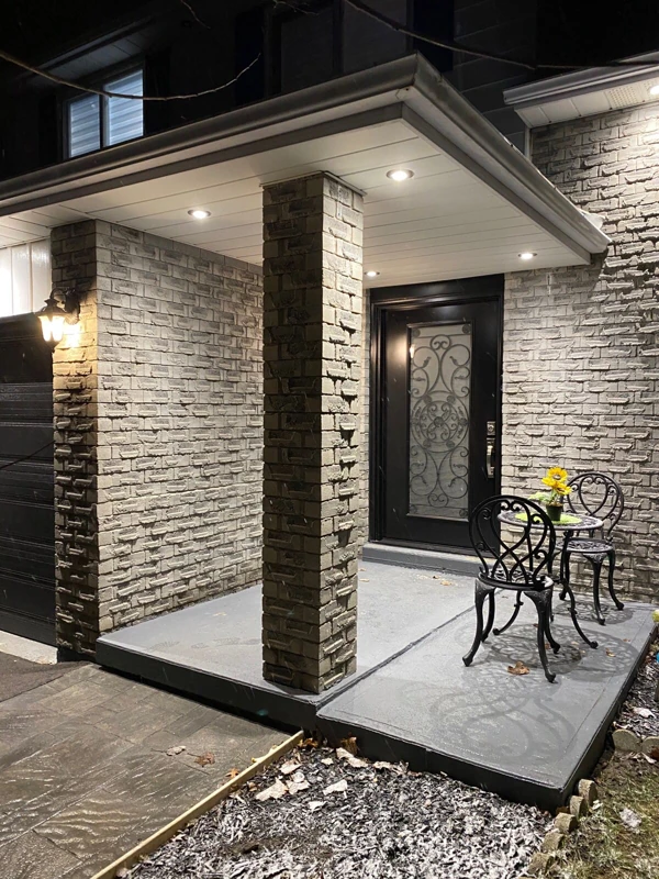 Recessed soffit lights illuminate a stone entry porch at night